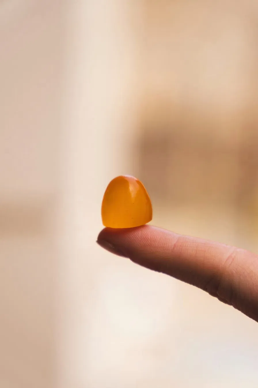 A single gummy held on a fingertip